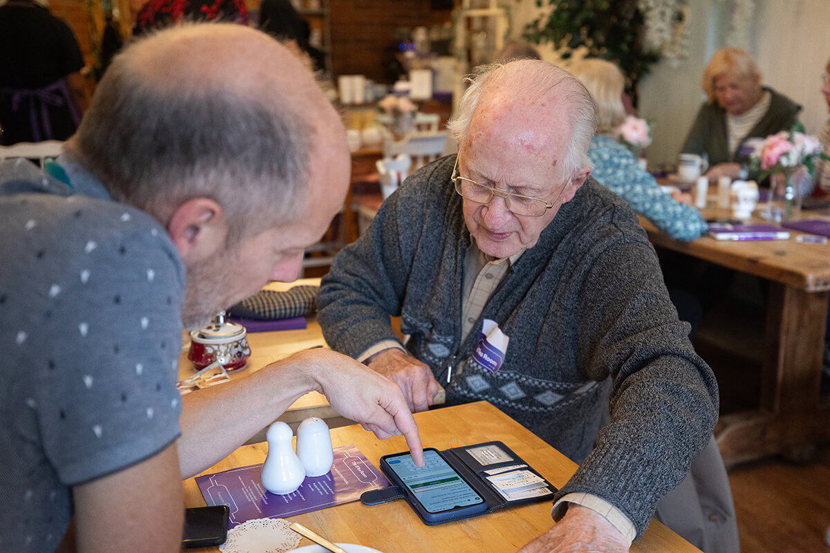 Helping elderly man with digital skills on his mobile phone