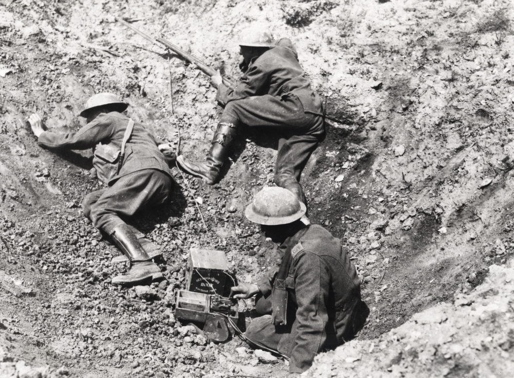 Wireless telegraphic operator using a Morse key in a shell hole, World War 1