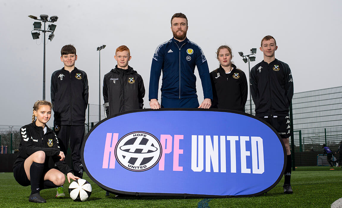 Grassroots football players behind Hope United banner