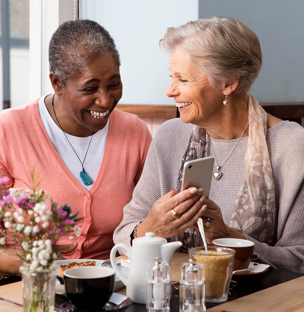 Two ladies sharing a laugh in a coffee shop