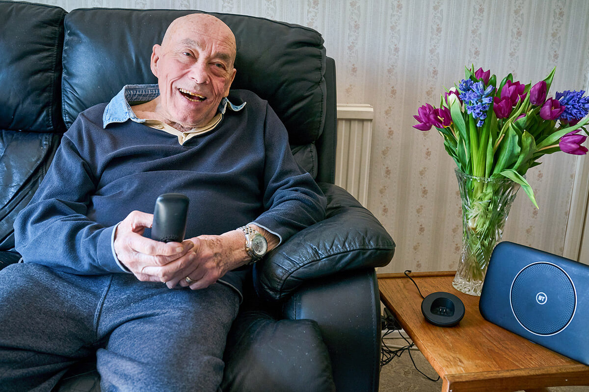 Elderly man sitting on a sofa with a cordless telephone