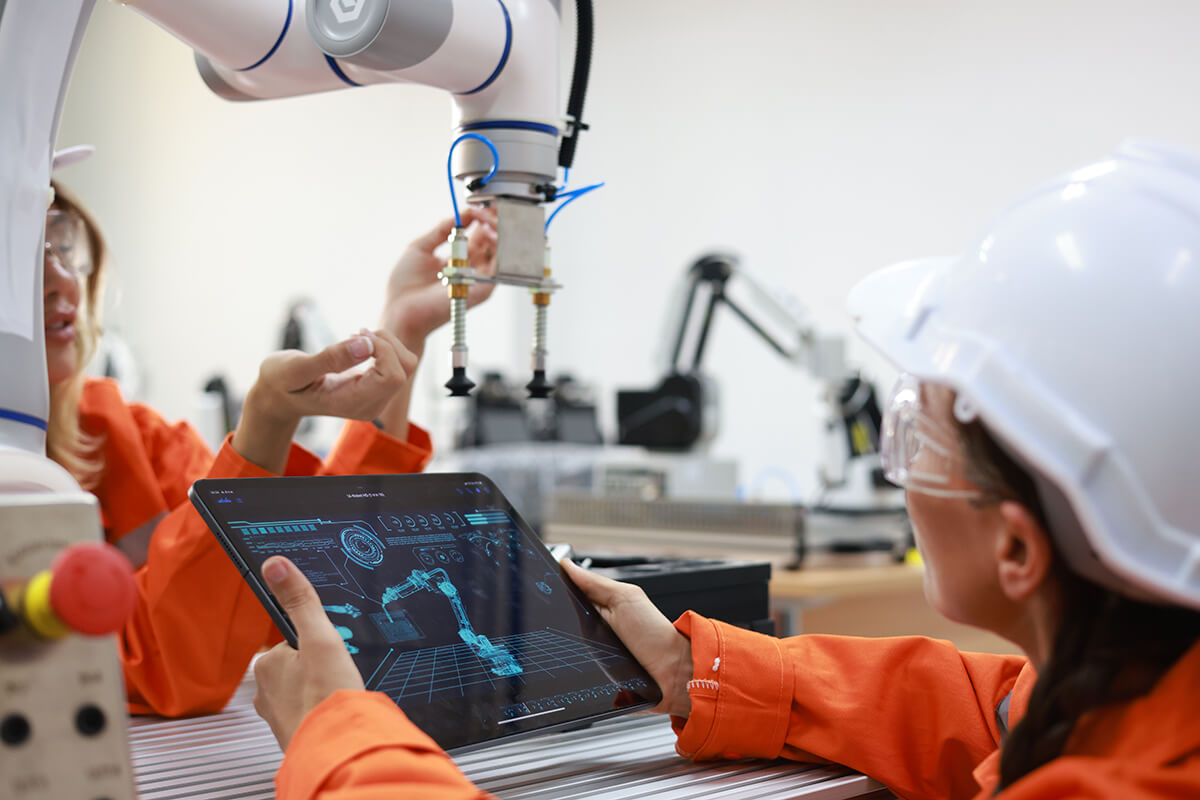 Female engineers working with digital tablet and robotic arm