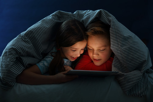 Children on tablet under a blanket