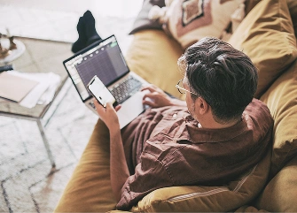 A person using multiple devices at home, representing seamless Wi‑Fi connectivity 