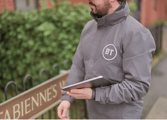 A BT broadband engineer holding a tablet outside a residential property