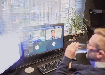 A person taking part in an online video meeting at a desk